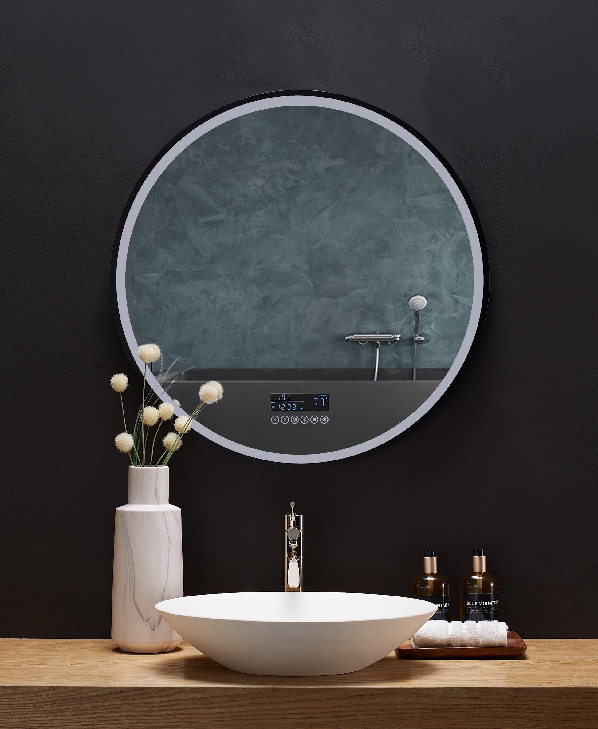 A round mirror is affixed above a bathroom vanity. The LED lighting around the edge of the mirror is on dim.