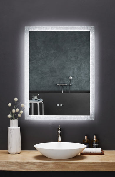 Image is a direct view of a rectangular Ancerre mirror above a bathroom vanity. Edge of mirror is illuminated.