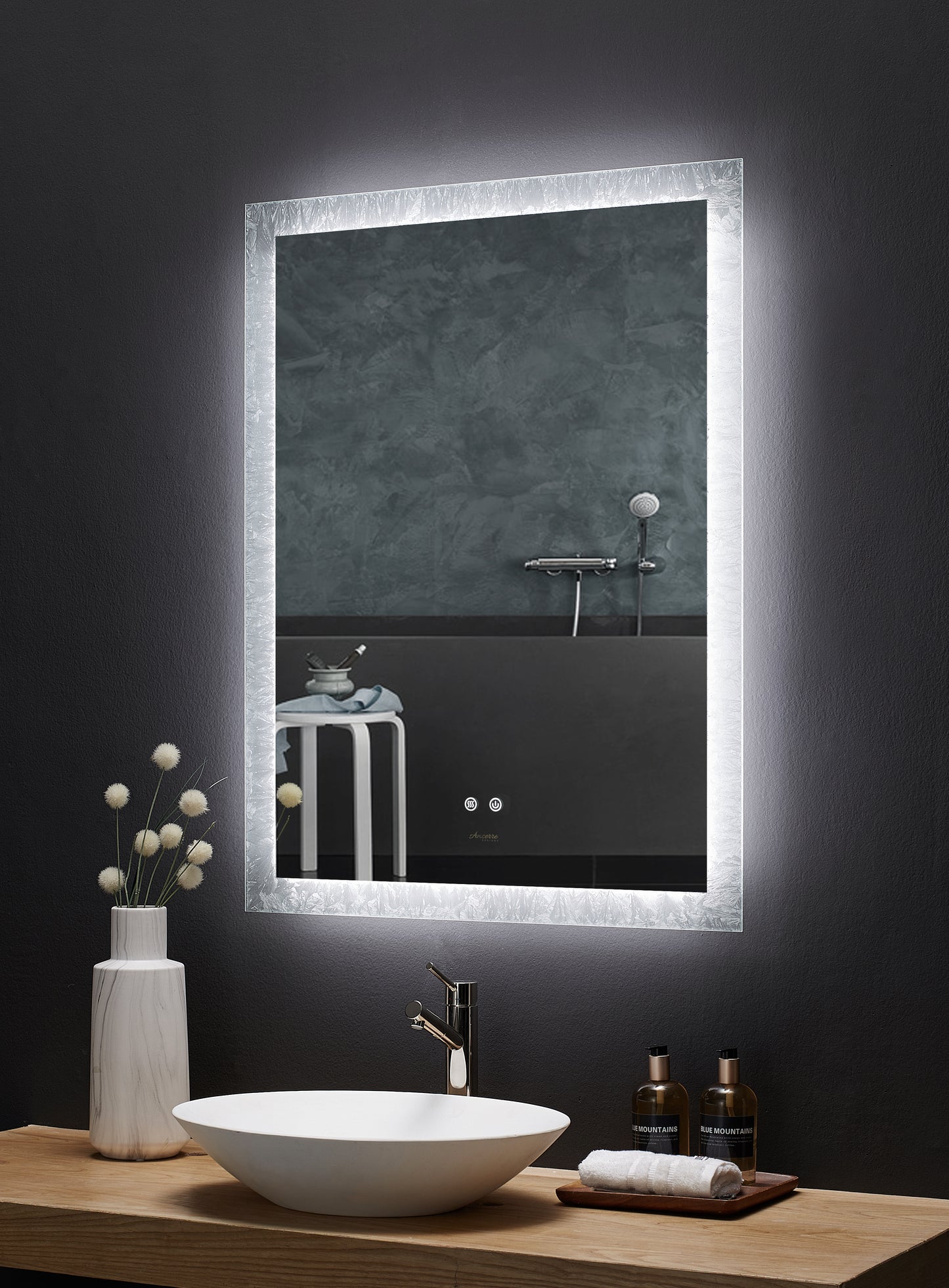 Image is a side angle view of a rectangular Ancerre Frysta mirror above a bathroom vanity.  LED edge lighting is on.